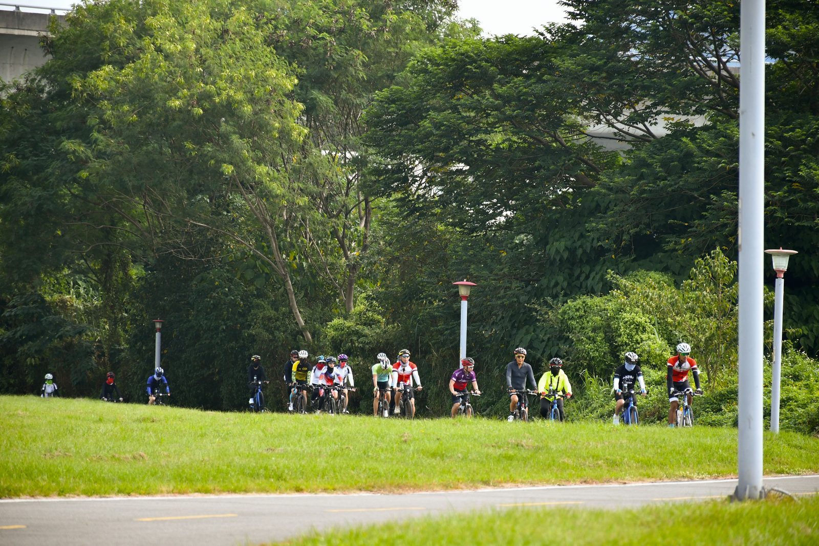 Riders strung out along a grassy path near the start