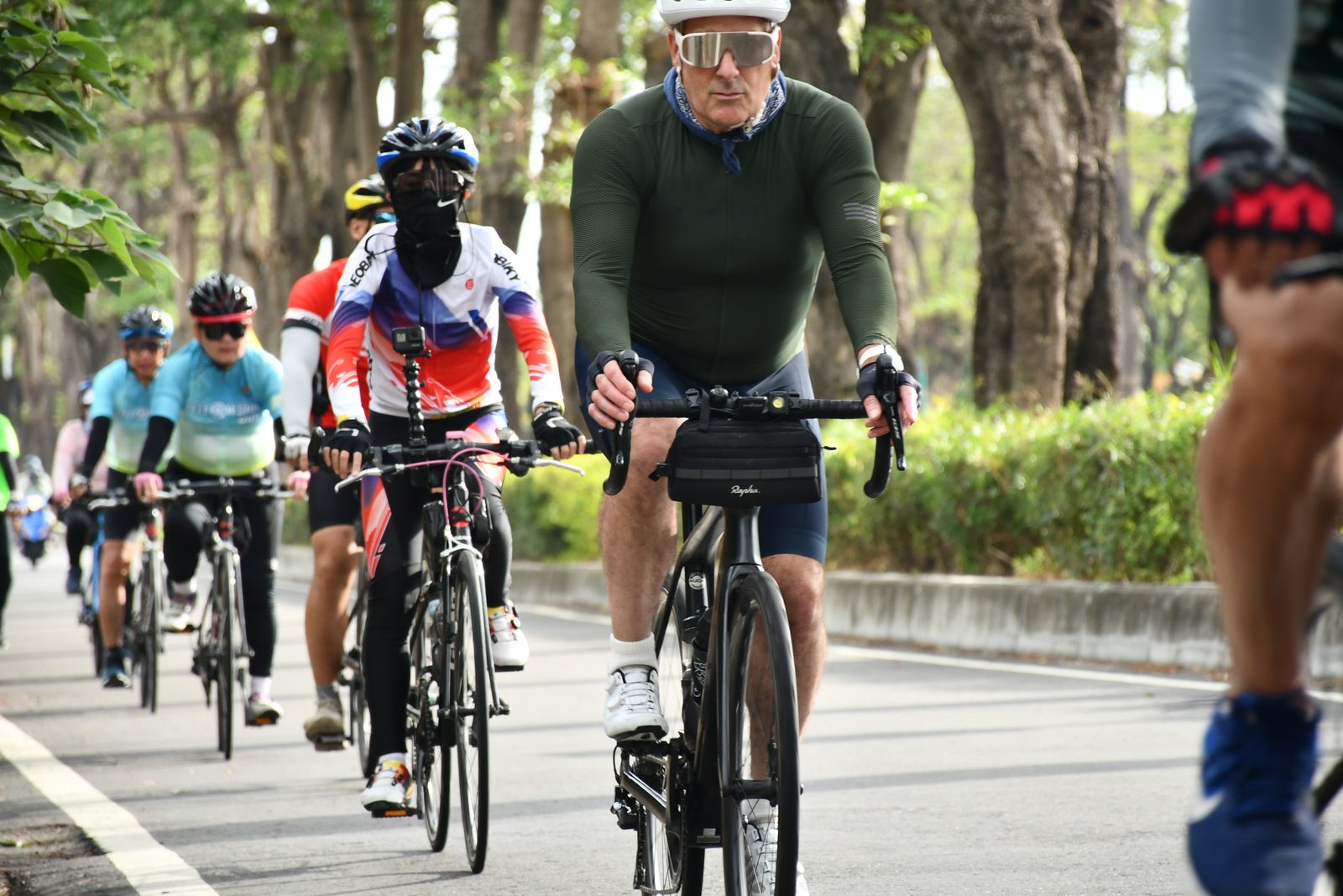 A rider in green leading a colorful group through the trees