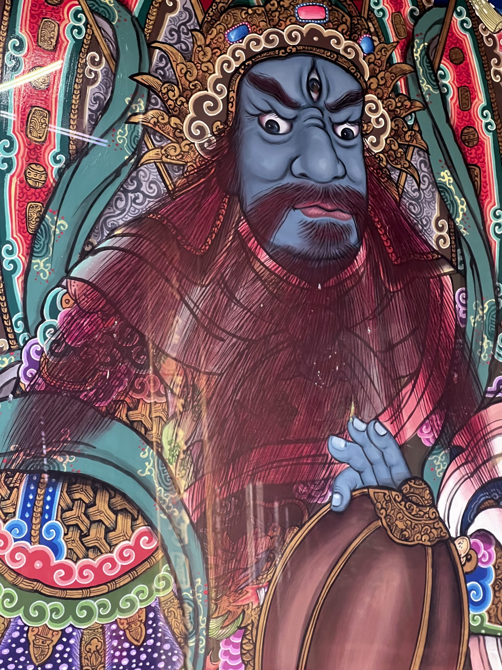 A vividly painted three-eyed guardian deity