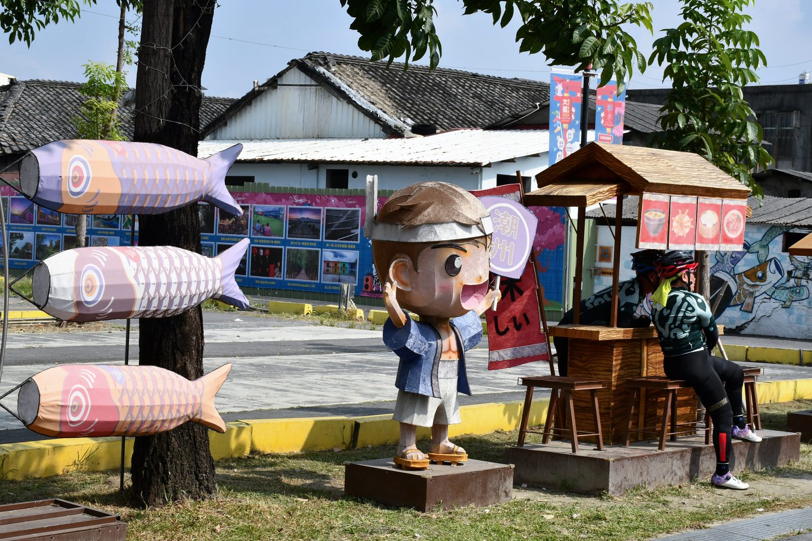 Koi windsocks and a boy mascot statue in town