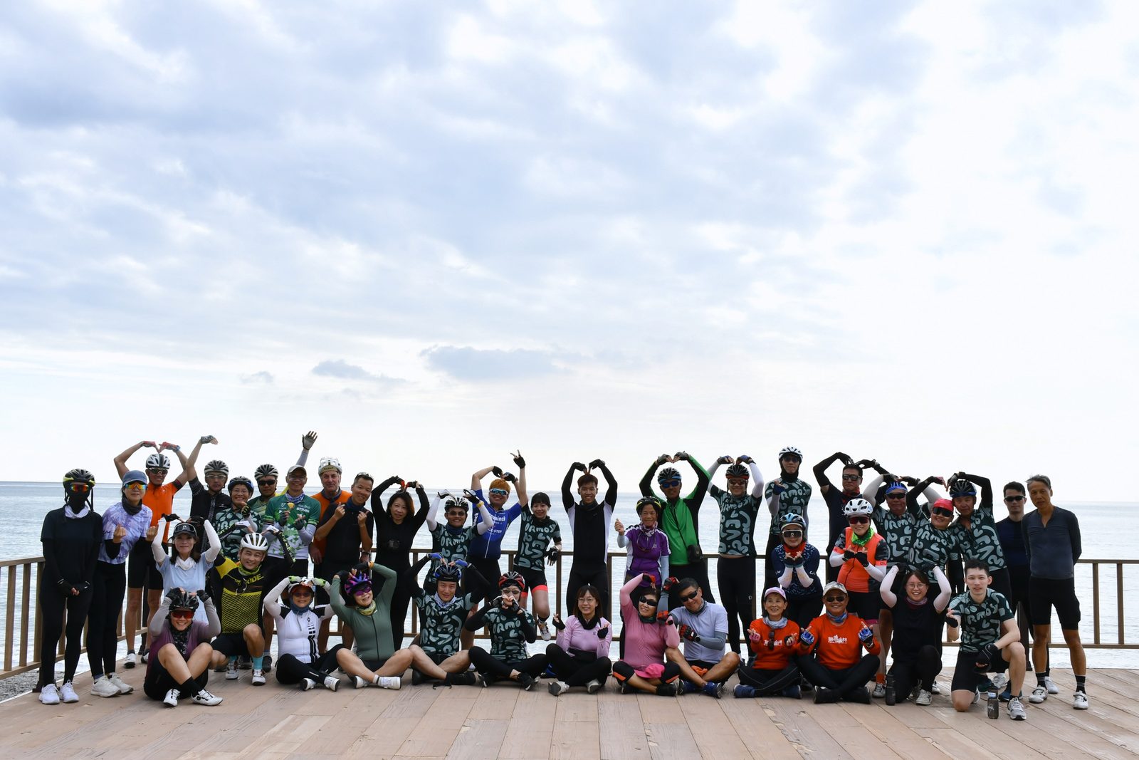 The whole group forming hearts on a beach boardwalk