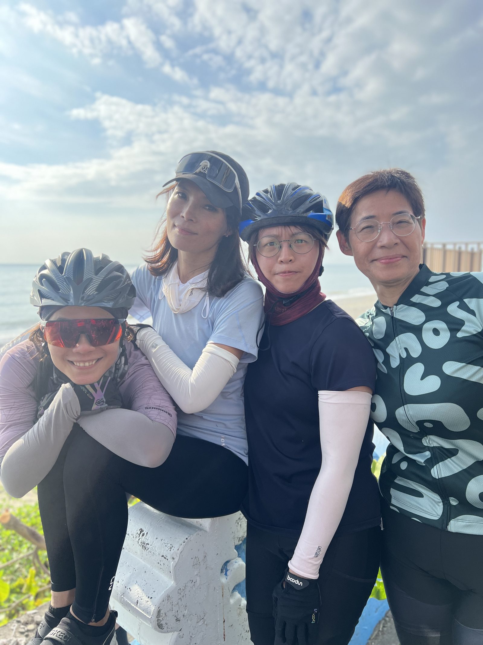 Four friends posed together by the sea
