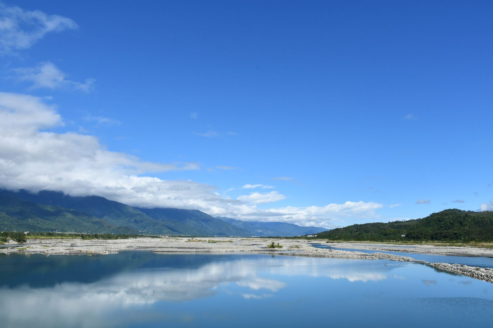 A wide valley view, mountains mirrored in still water